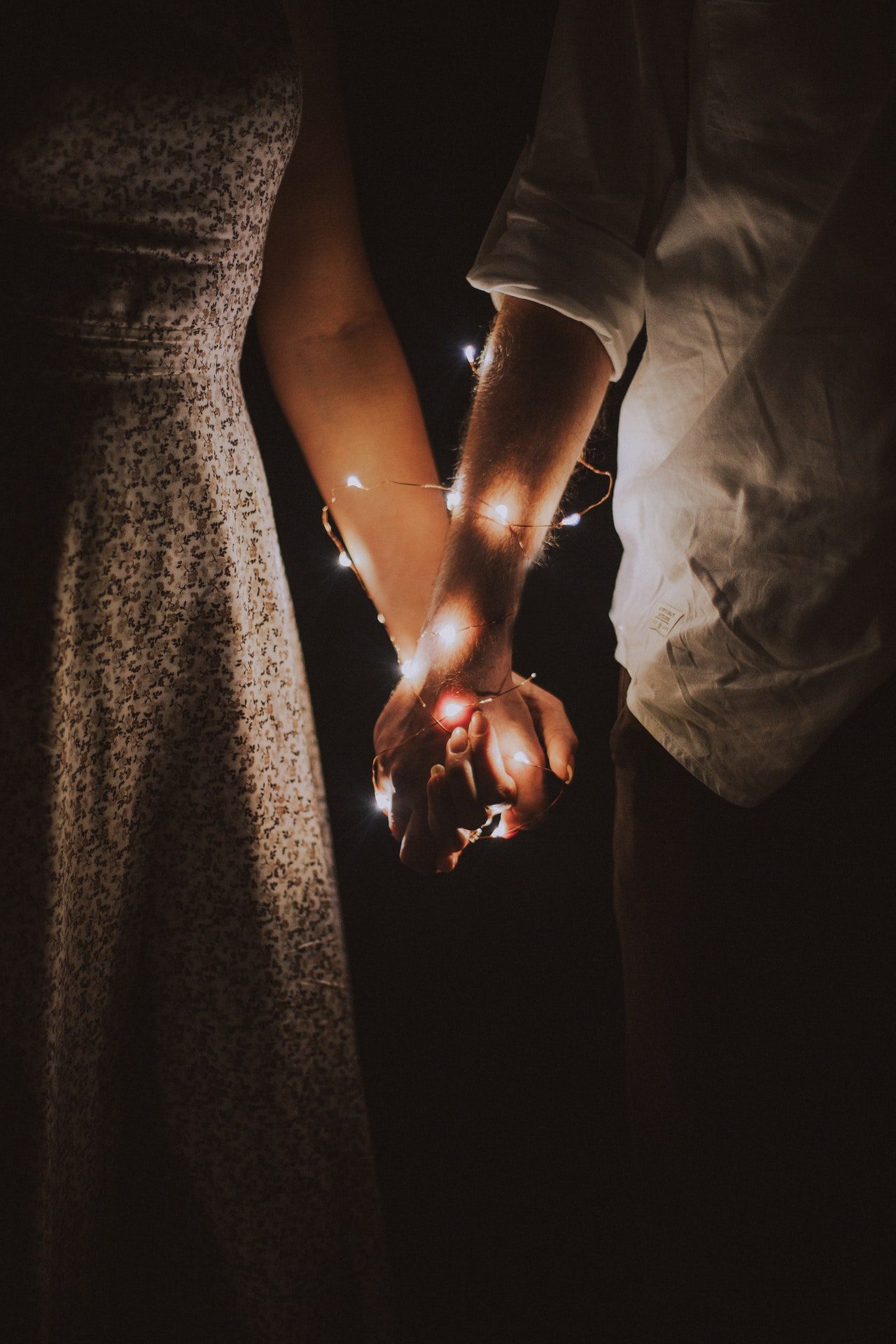 Photo by Anastasiya Lobanovskaya from Pexels https://www.pexels.com/photo/man-and-woman-holding-each-others-hand-wrapped-with-string-lights-792777/